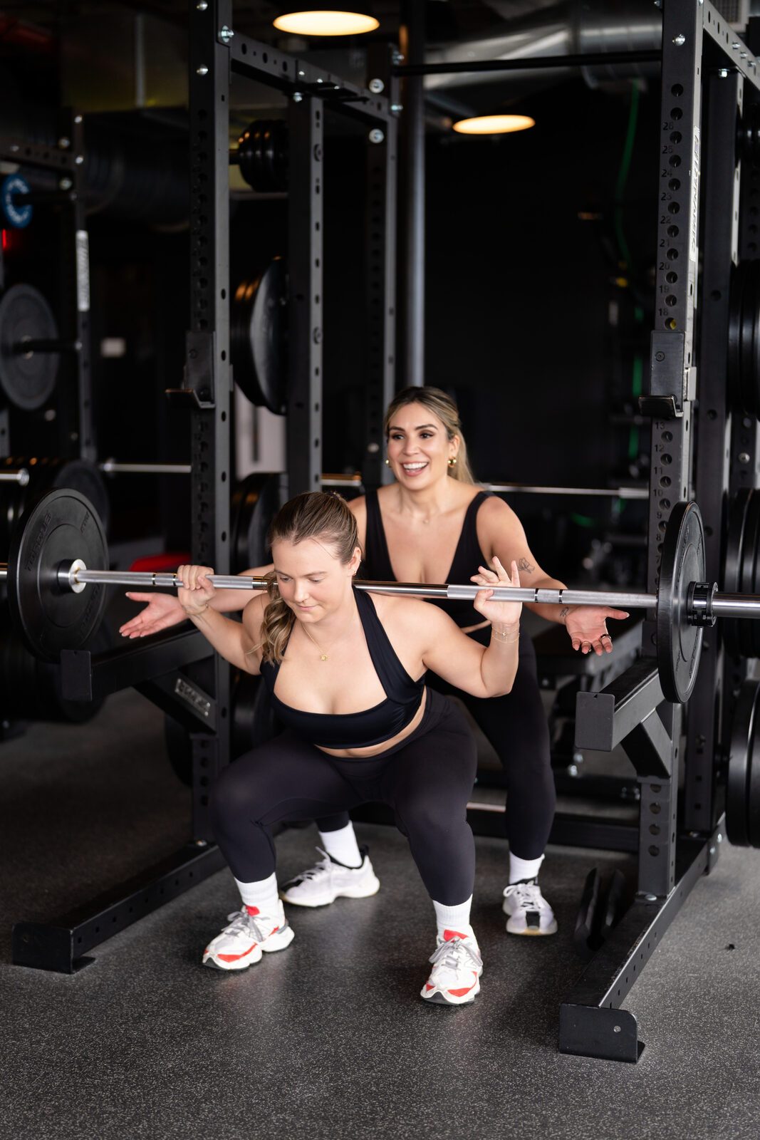 Carolina spotting a client's barbell back squat