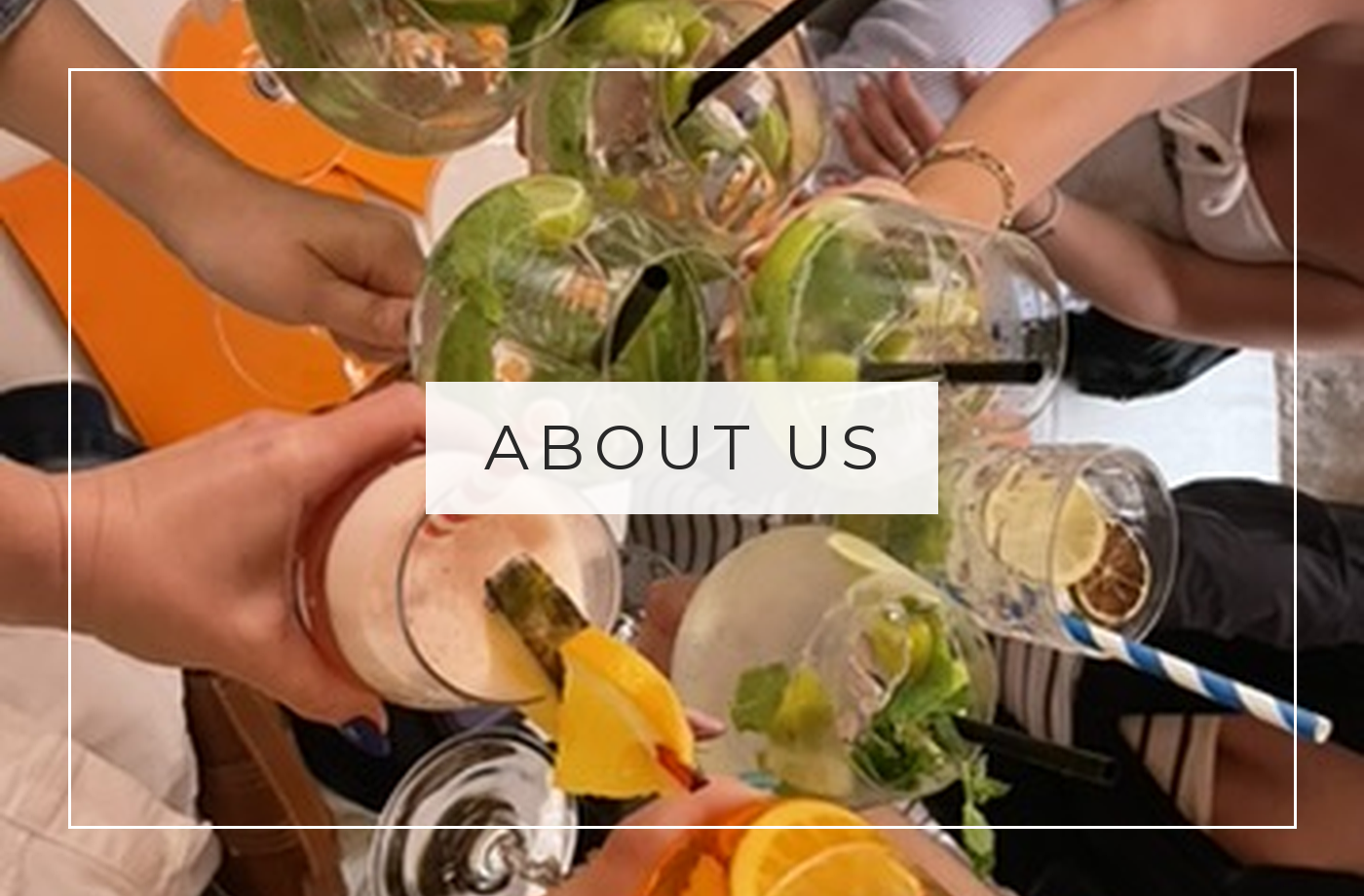 About us: friends toasting with cocktails around a table