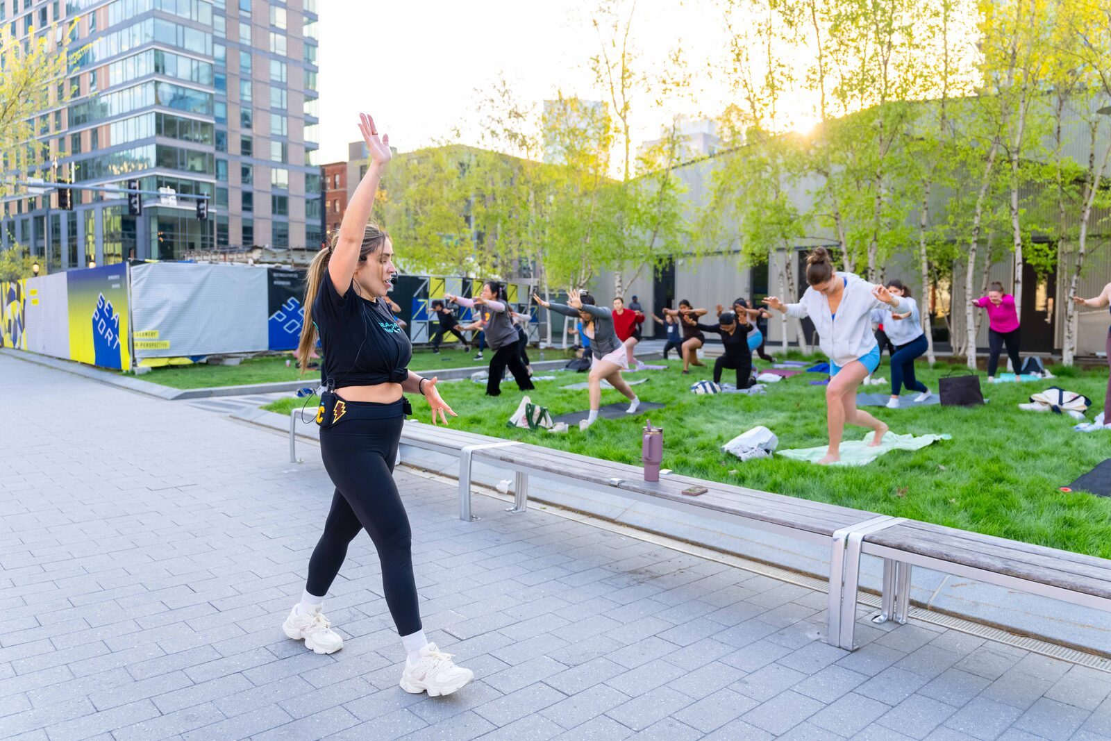 Carolina teaching an outdoor strength class with the group behind her in warrior pose